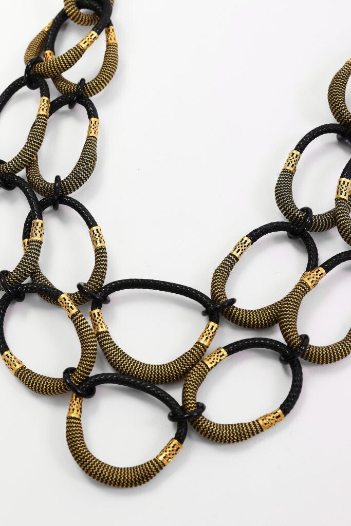 Close-up of Naya black and gold statement necklace with textured linked loop design