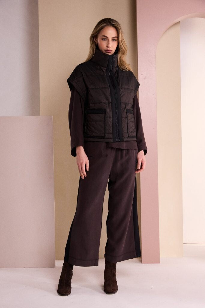 Naya padded waistcoat with high funnel neck and contrast front zip worn layered over a long sleeve top